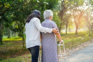 Woman helping an elderly woman walk outside with a walker