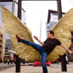 aaron blight in front of winged statue