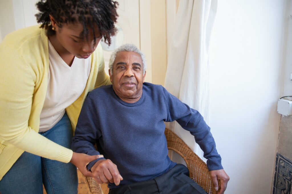 caregiver helping elderly man out of chair