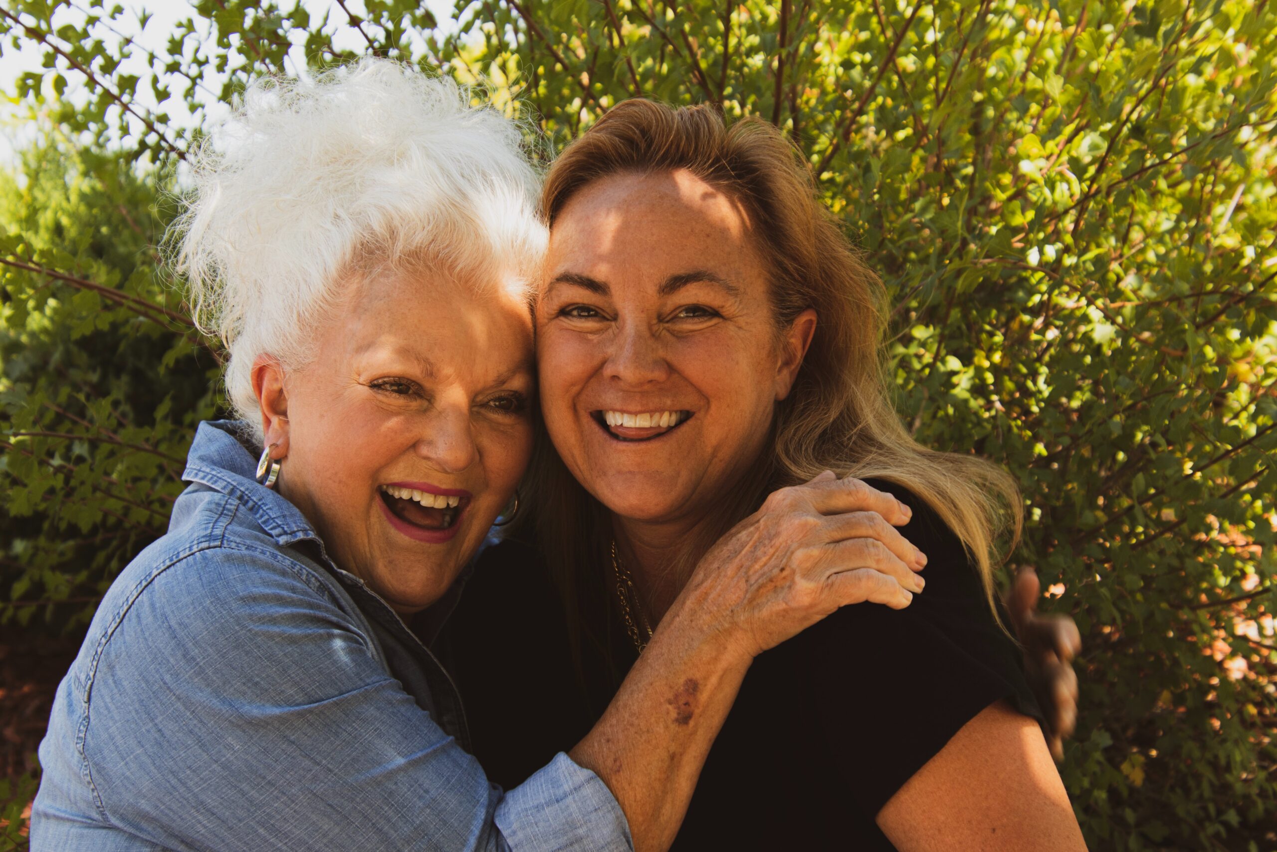 older woman and caregiver hugging and smiling
