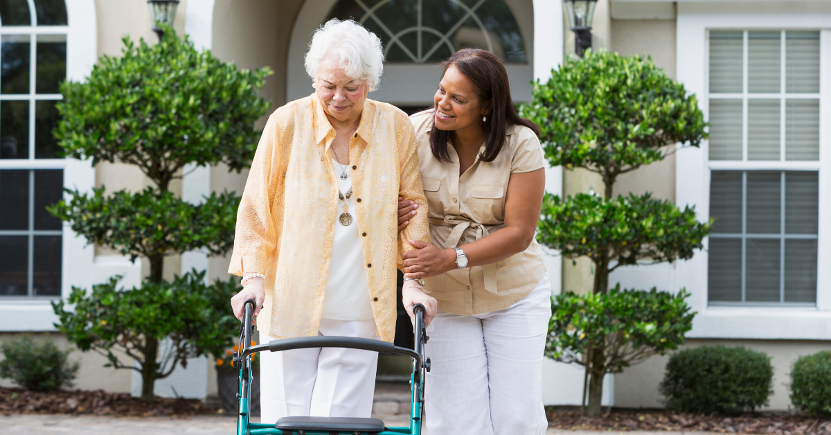 woman helping elderly mother walk outside