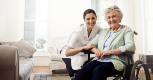 healthcare worker smiling and kneeling next to elderly woman