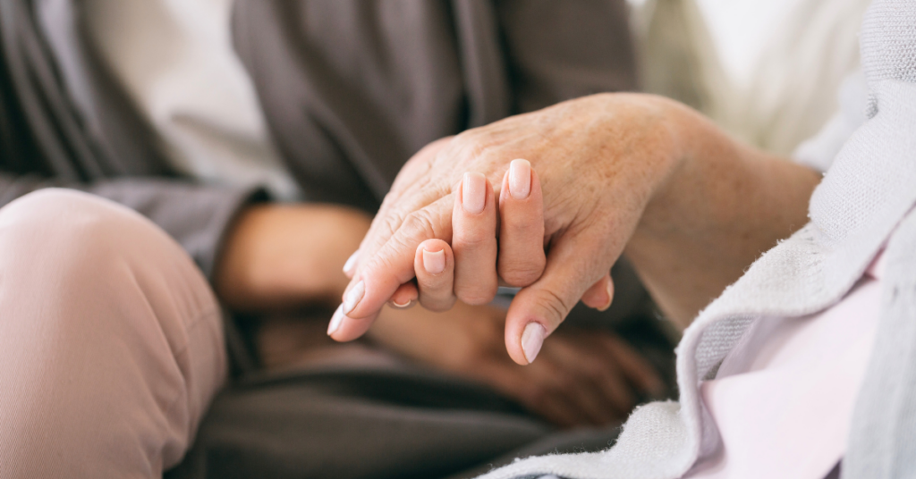 caregiver holding mother's hand