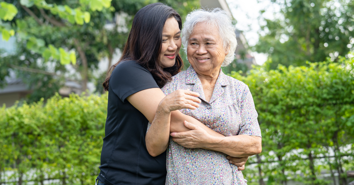Adult daughter hugging her elderly mother as they walk