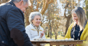 Elderly couple playing dominoes with their adult daughter